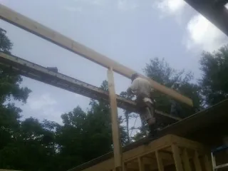 Carpenter setting a ridge beam over a new addition frame — Ice Dam Removal by Roofing Brothers in Wellesley