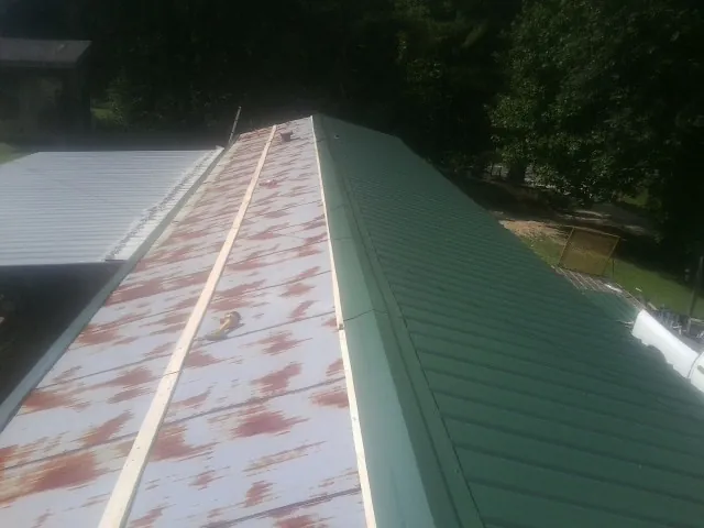 Old rusted panels beside newly installed green metal roofing — Wind Damage Roof Repair by Roofing Brothers in Wellesley
