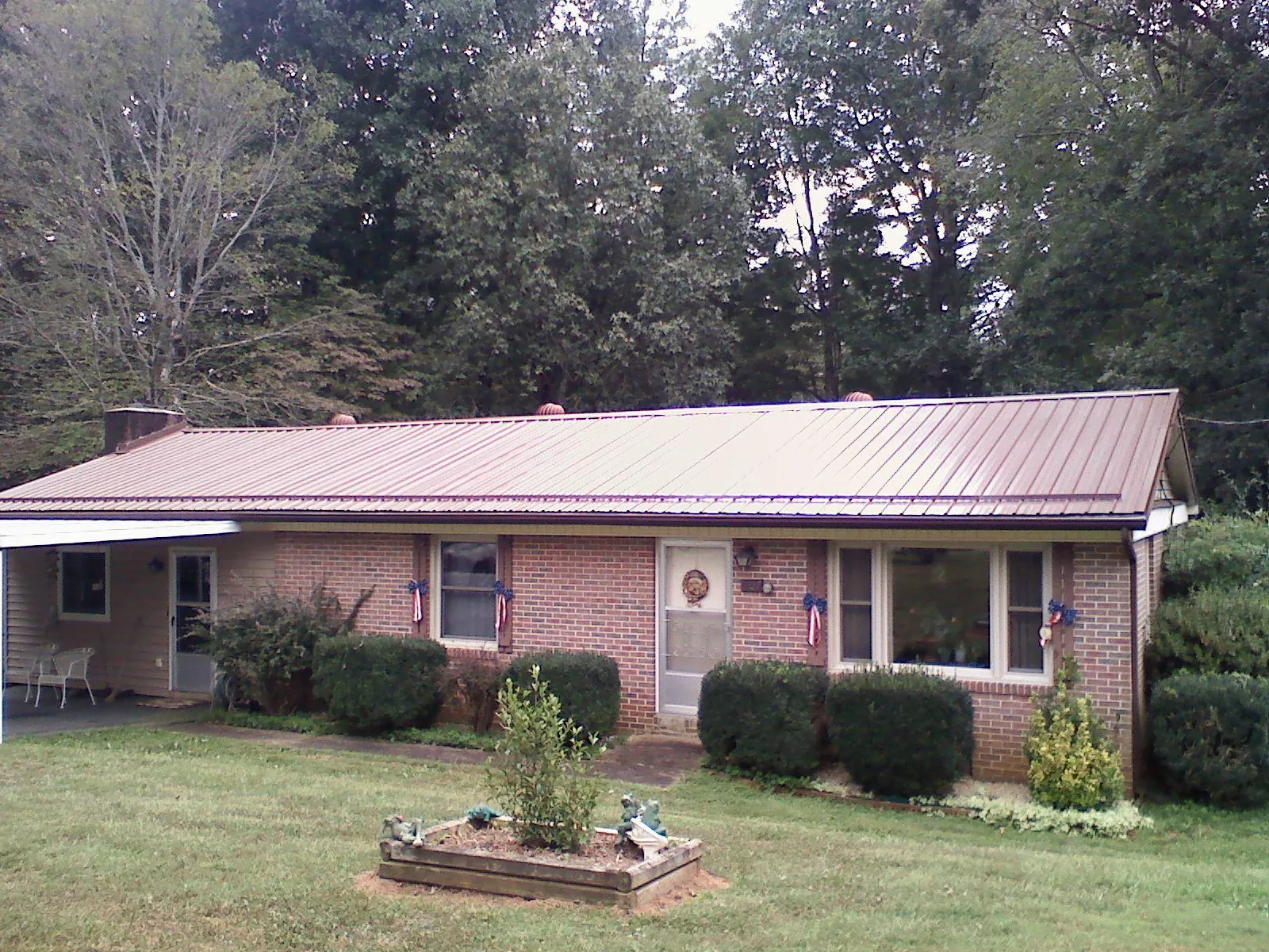 Bronze metal roof on a brick ranch home with a carport in Wellesley