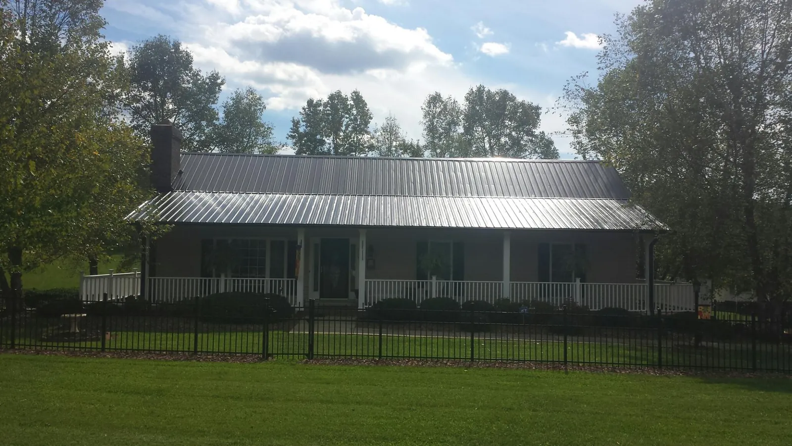 Gray metal roof on a brick ranch with a full width front porch — Gutter Guard Installation work by our crew in Wellesley