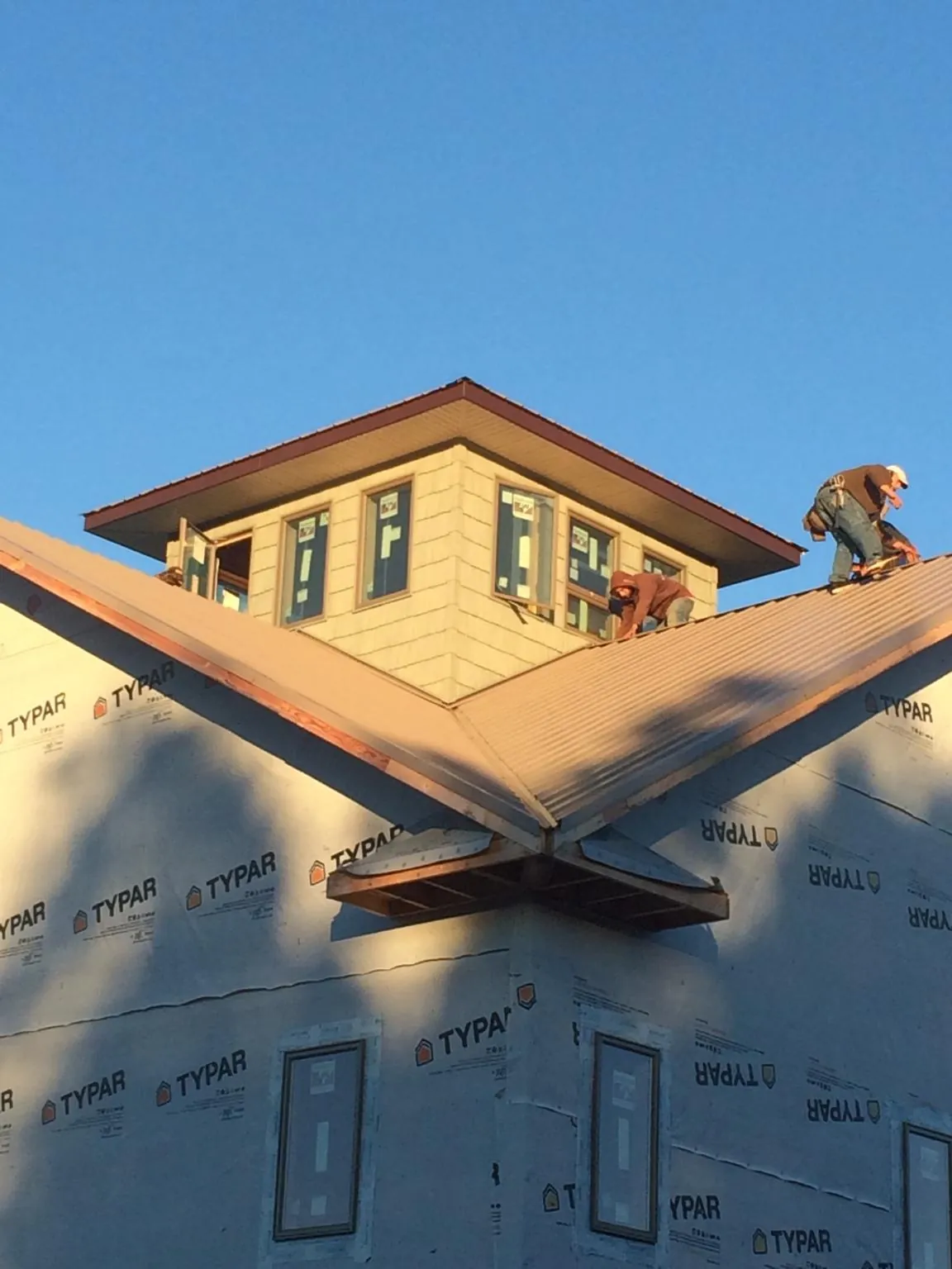 Roofers working around a rooftop cupola on a new metal roof at sunset — Roof Waterproofing in Wellesley by Roofing Brothers